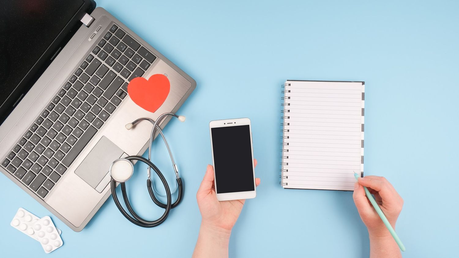 ordinateur, téléphone mobile, stéthoscope et calepin posés sur une table